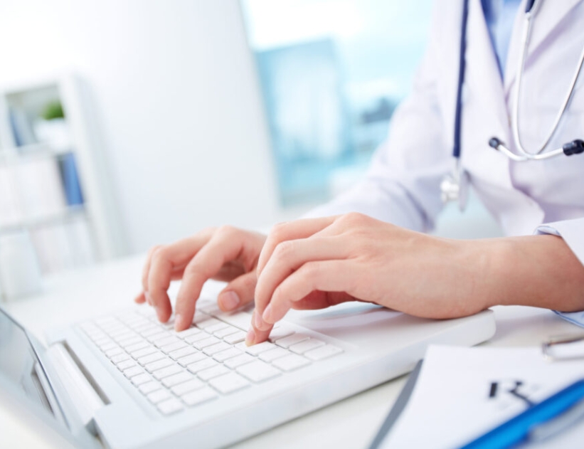 Close-up of hands of a nurse typing on laptop